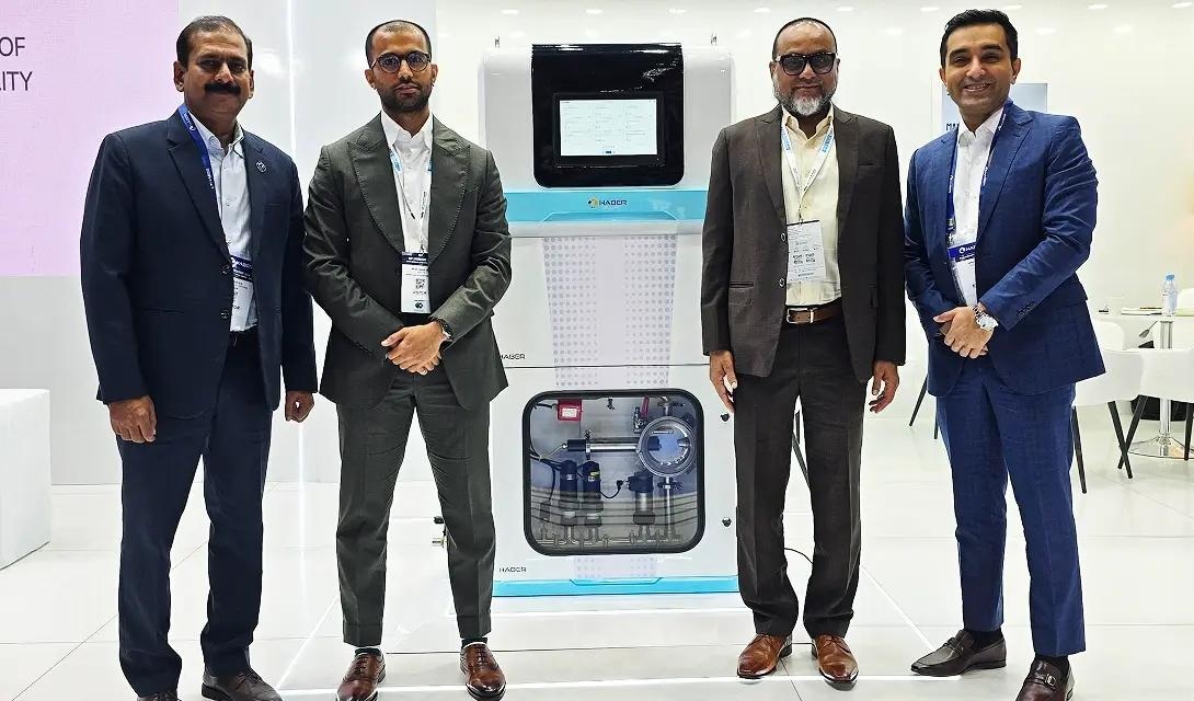 Four people standing beside a Haber industrial monitoring and sampling unit