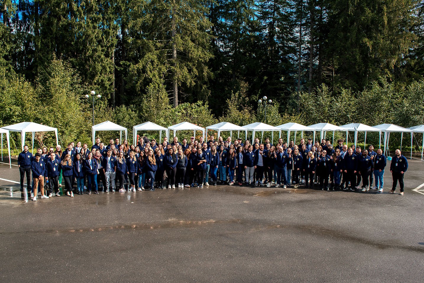 hackajob colleagues gathered outdoors in front of a line of white shelters and trees