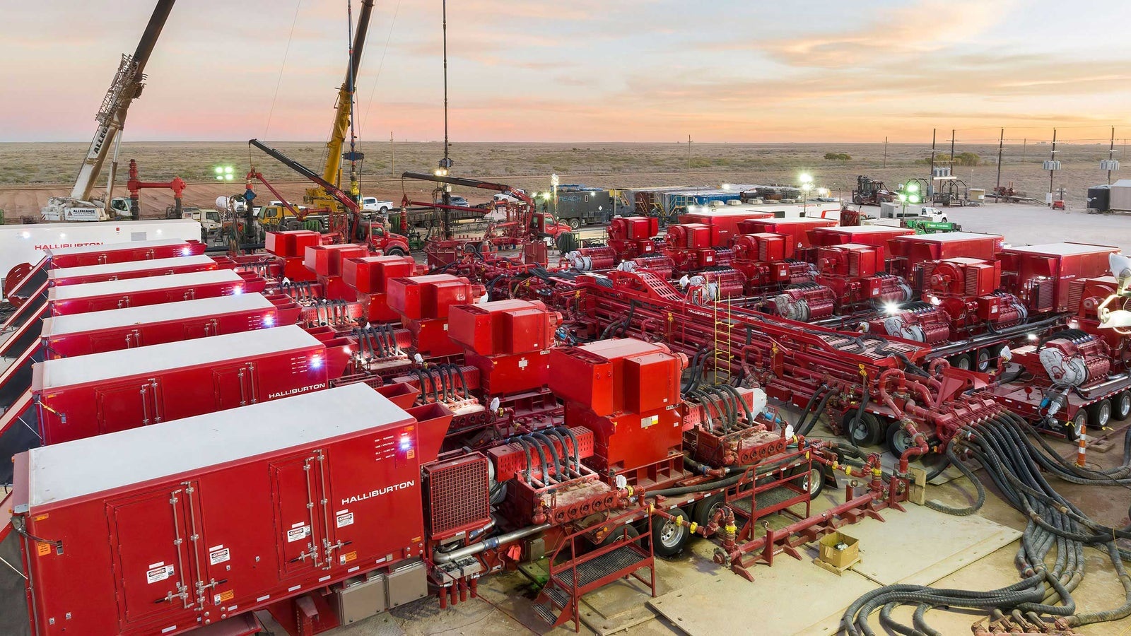 Rows of red Halliburton ZEUS electric pumping equipment connected by pipes at a well site