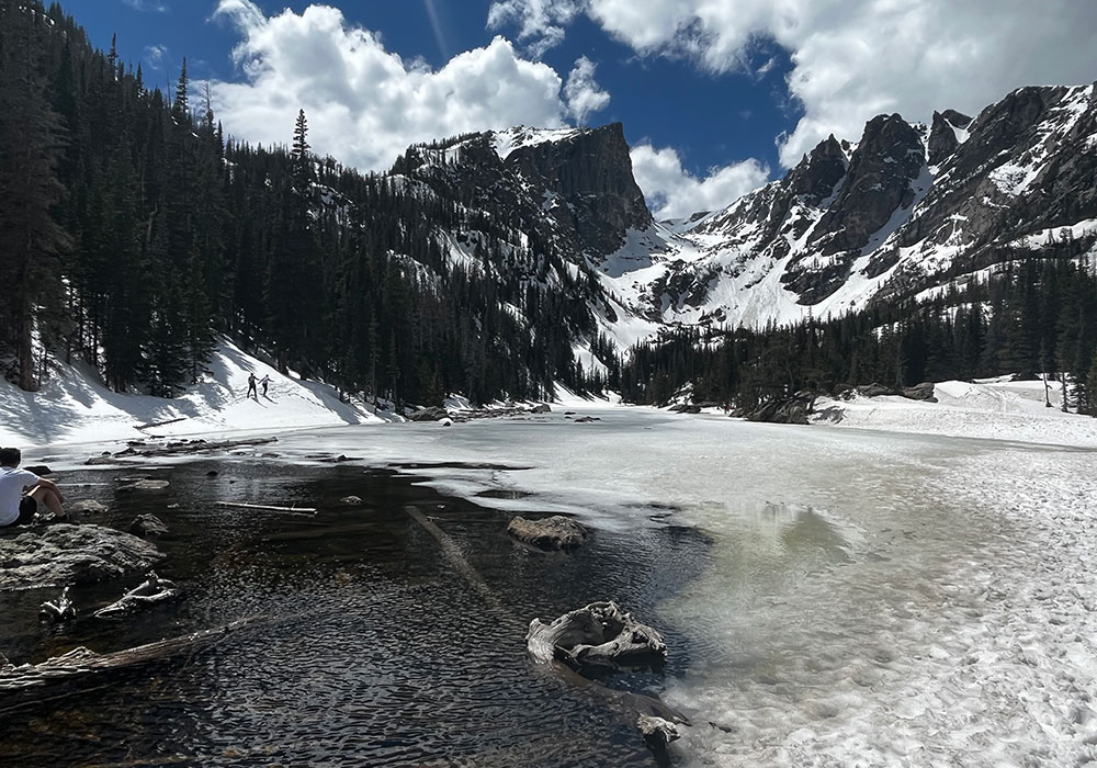Snow-covered mountains and a partially frozen lake pictured in Babai’s team-hike essay