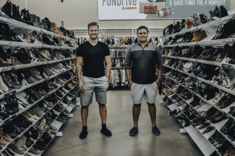 HAMMOQ co-founders Ty Blunt and Sid Lunawat standing between shelves of secondhand shoes