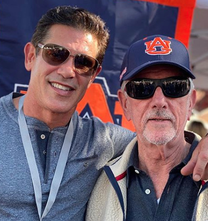 Hank McLarty standing beside his father at an Auburn-Alabama football game