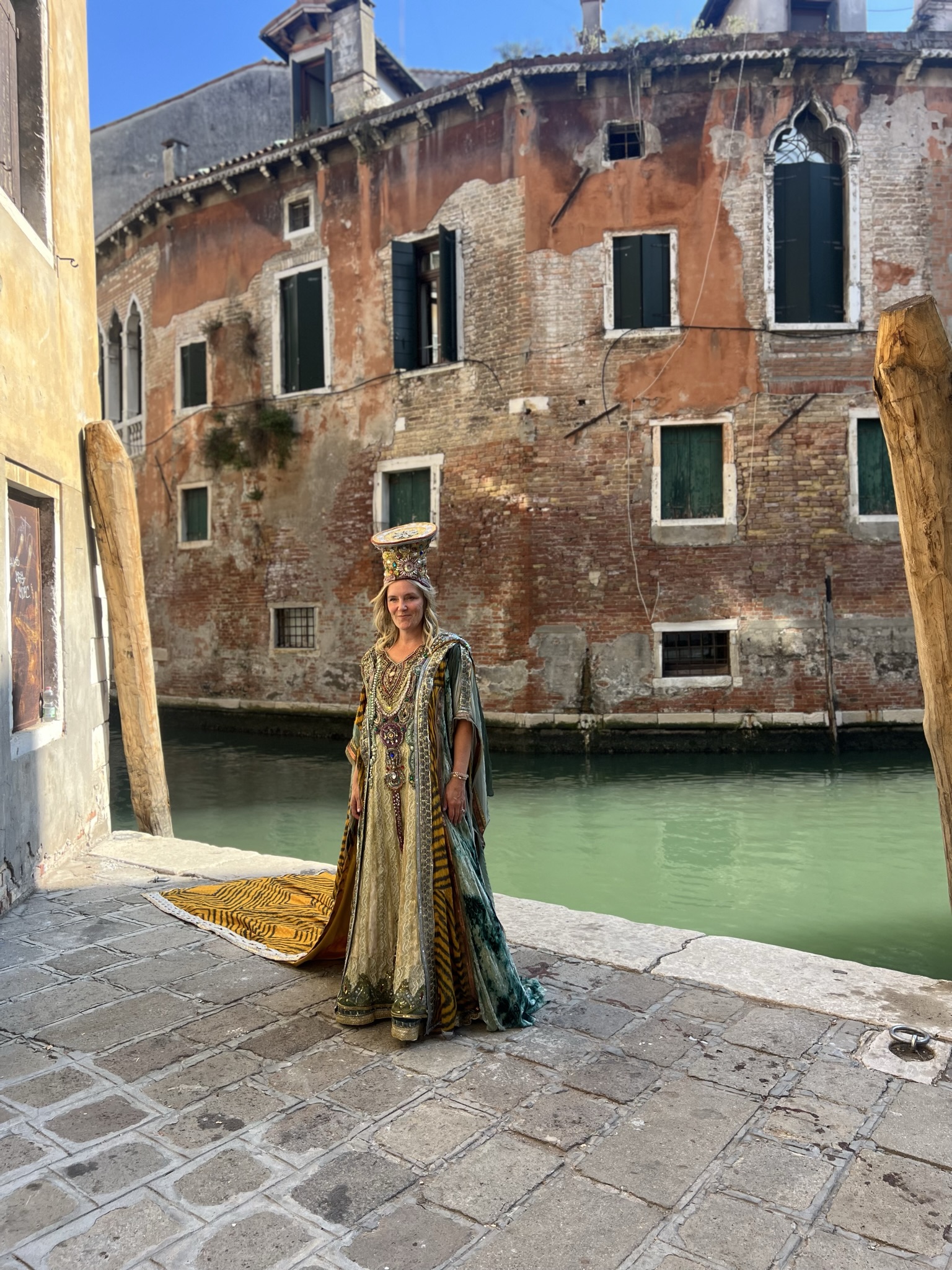 Hannah Kratz in an ornate costume beside a canal and weathered buildings