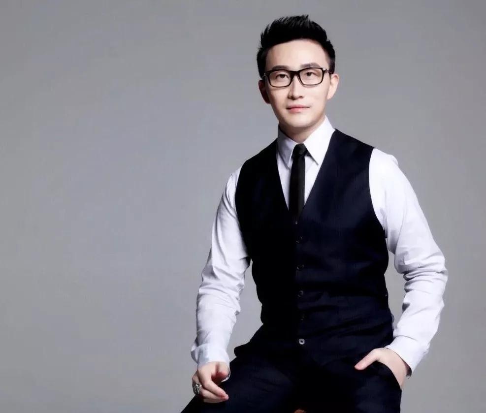 Hao Zhou in a formal portrait wearing glasses, a white shirt and dark waistcoat