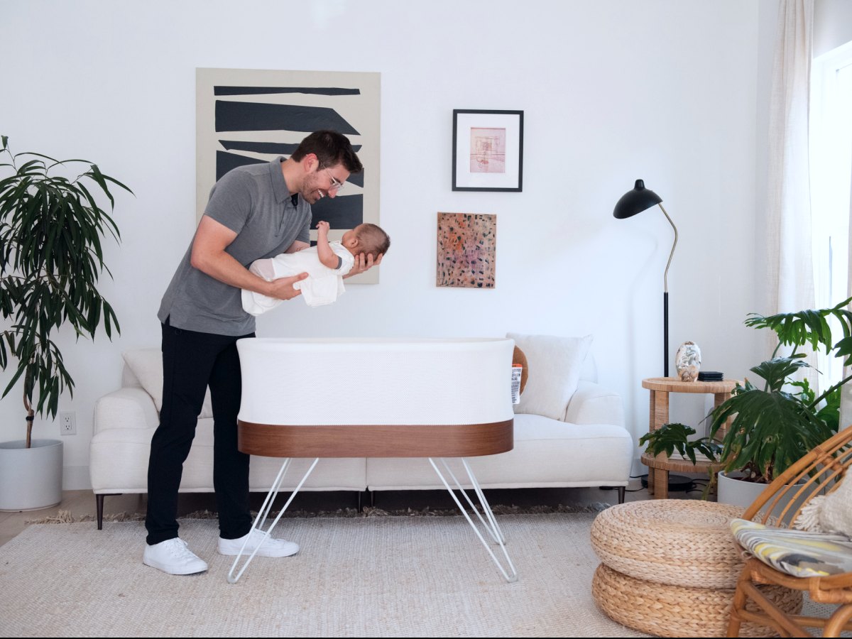 A parent lowering a swaddled baby into the SNOO bassinet