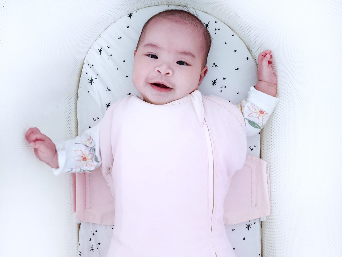 A baby resting in the SNOO swaddle inside the bassinet