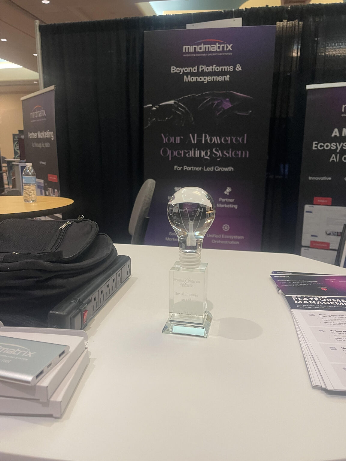 Mindmatrix’s AI Pioneer award, photographed on a table in front of the company’s event display.