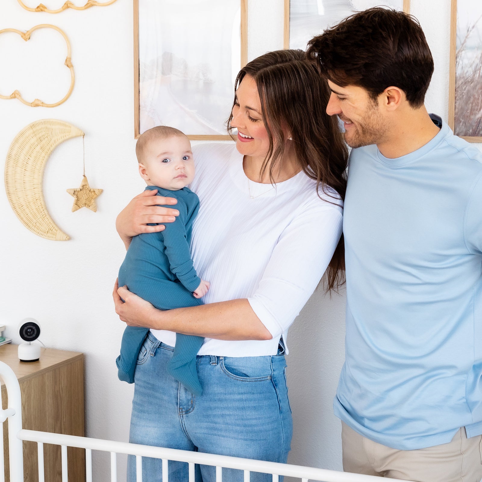 Parents holding their baby in a nursery with a Harbor camera on the nightstand