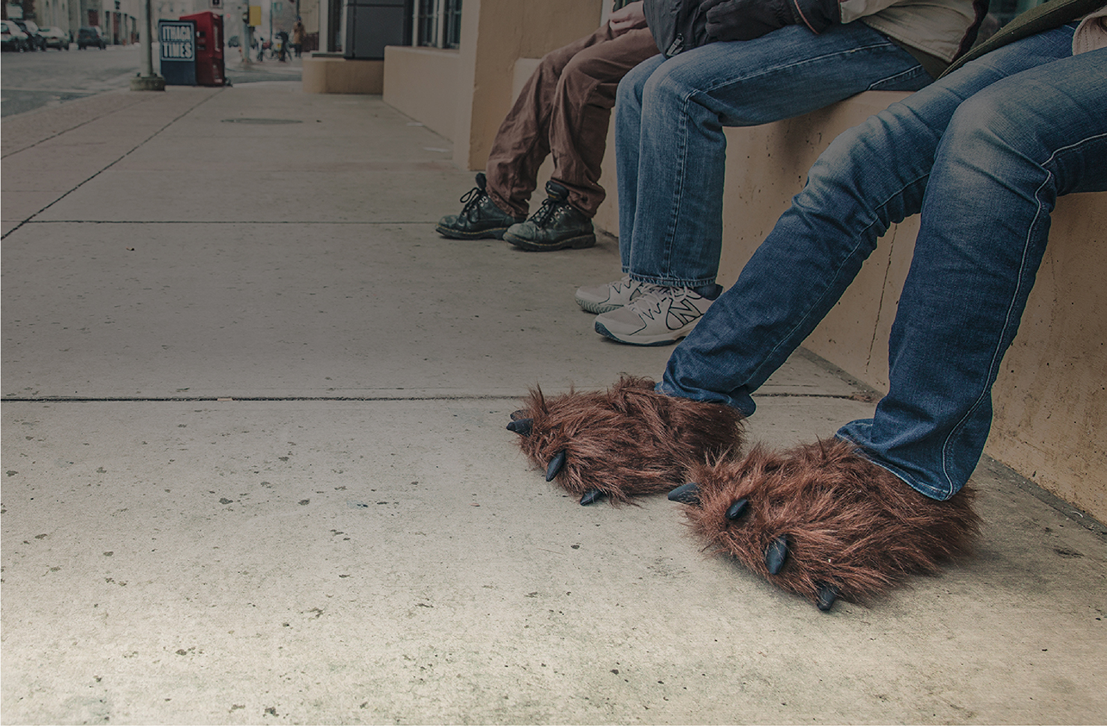 A seated person wearing oversized brown furry animal slippers in an official Harding Marketing brand image