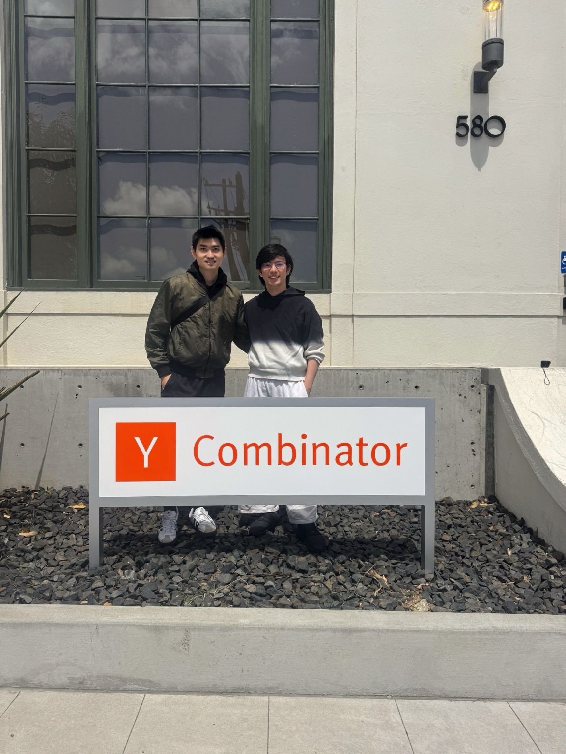 Harry Zheng and Edward Ma standing behind the Y Combinator sign in Mountain View