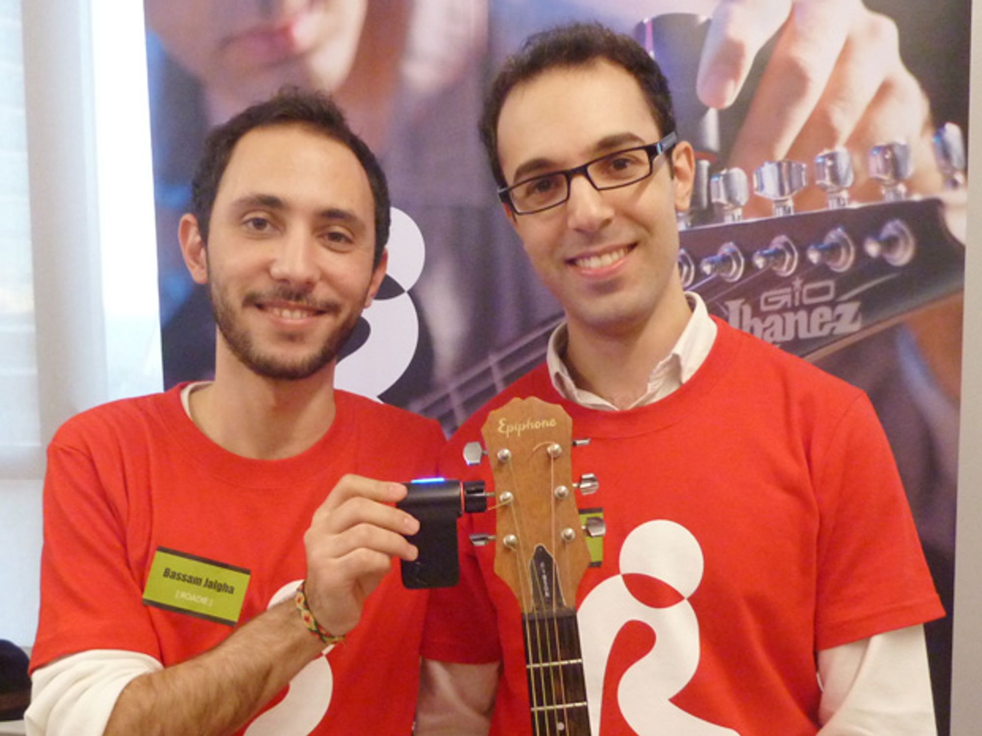 Bassam Jalgha and Hassane Slaibi in red shirts demonstrating an early Roadie tuner on a guitar