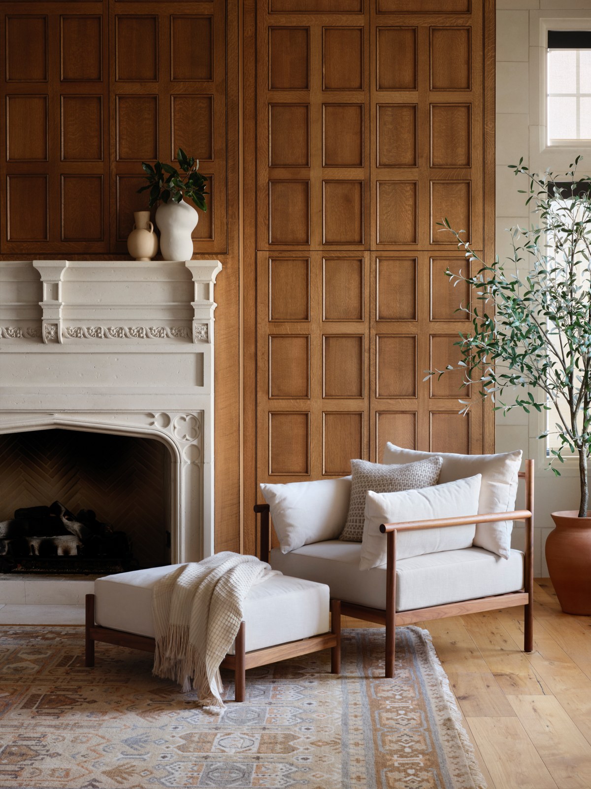 The Citizenry Santo linen armchair and ottoman beside a wood-paneled fireplace