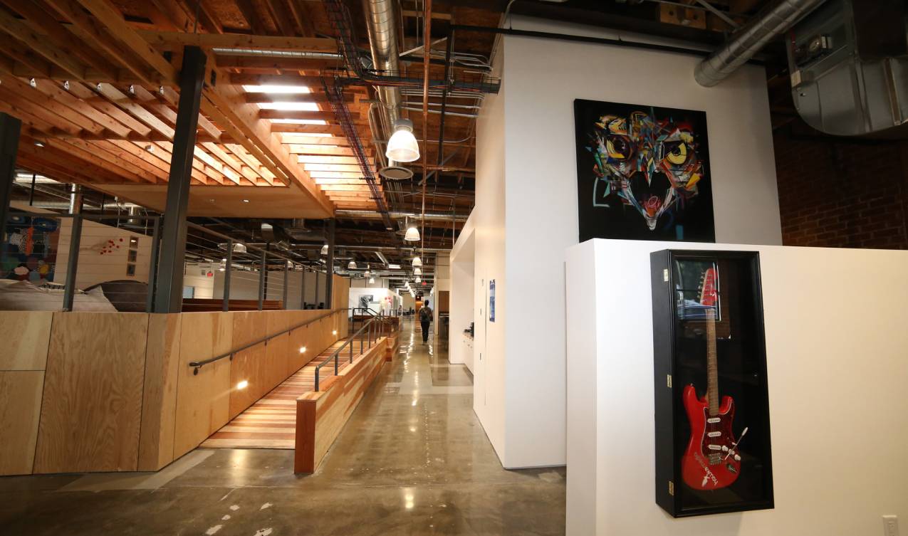 A Hawke Media office interior with exposed timber, open workspaces and a red guitar in a display case