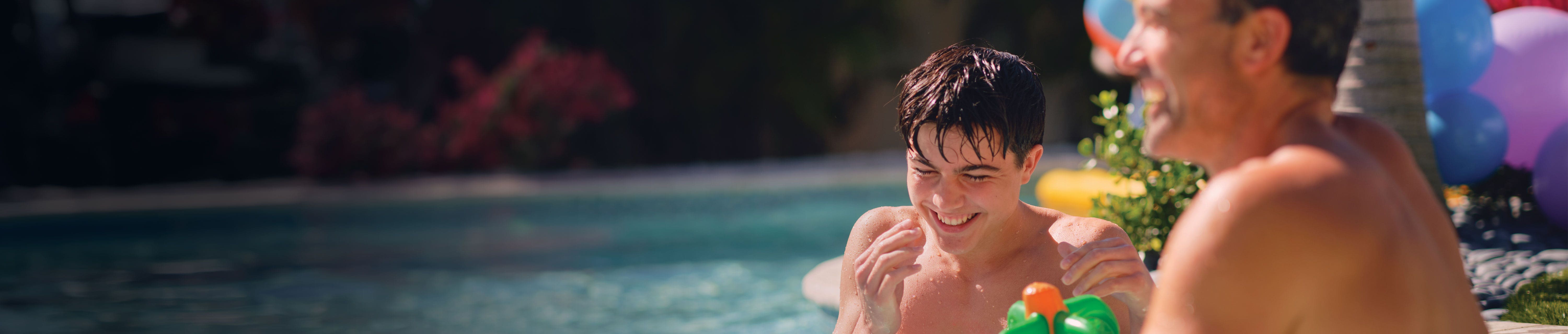 A father and son playing together in an outdoor swimming pool
