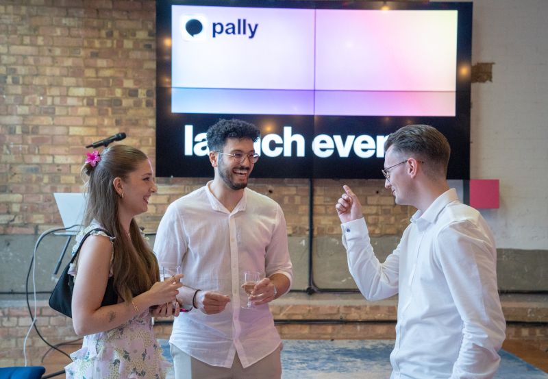 Guests talking at a Pally launch event in front of a large Pally display