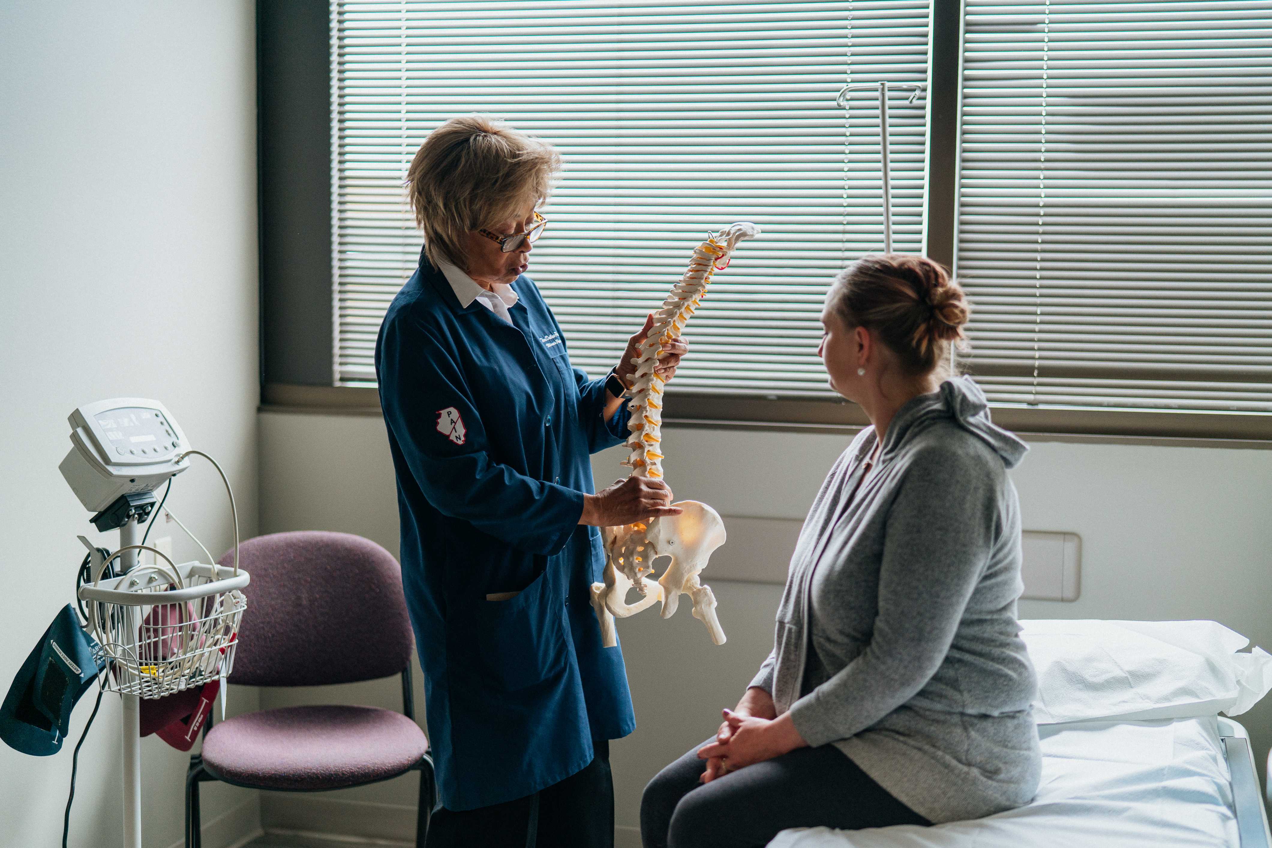 A clinician uses an anatomical spine model to explain care to a seated patient