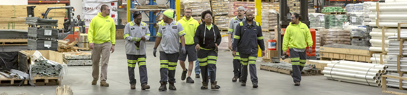 Warehouse associates in safety gear walking between shelves of inventory