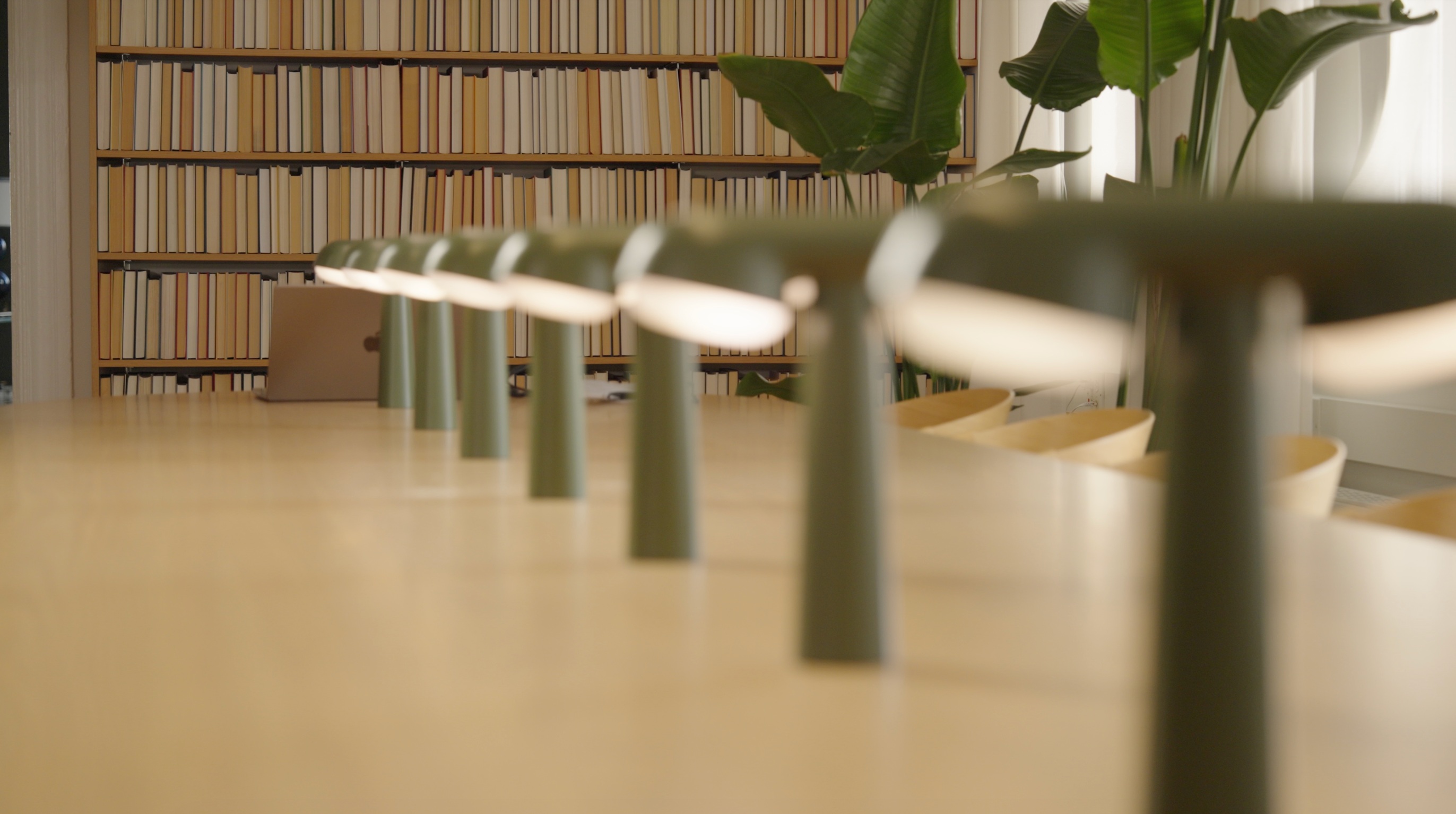 A meeting table with green lamps and bookshelves, pictured on Headline’s About page