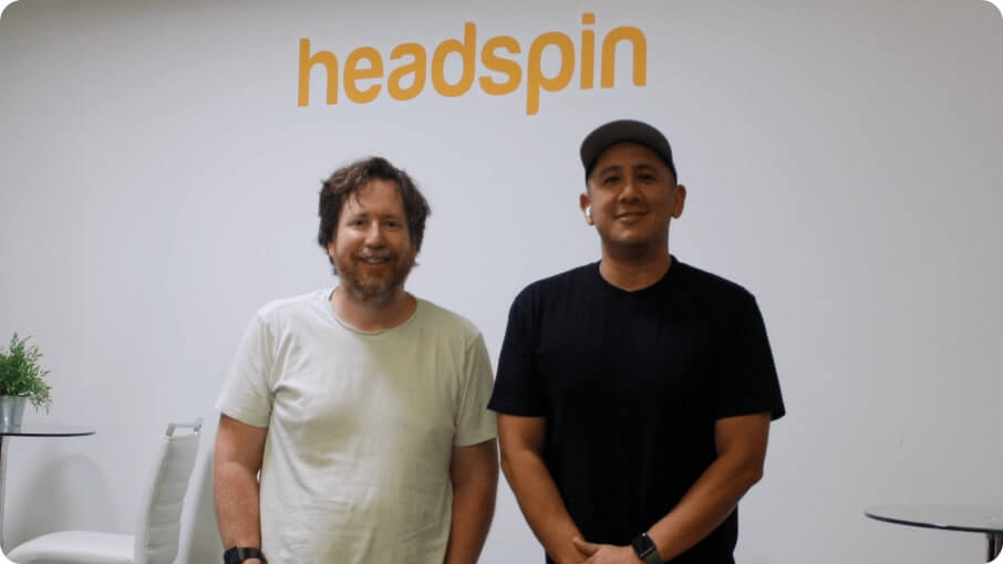 Two people photographed in a HeadSpin workplace beneath the company name