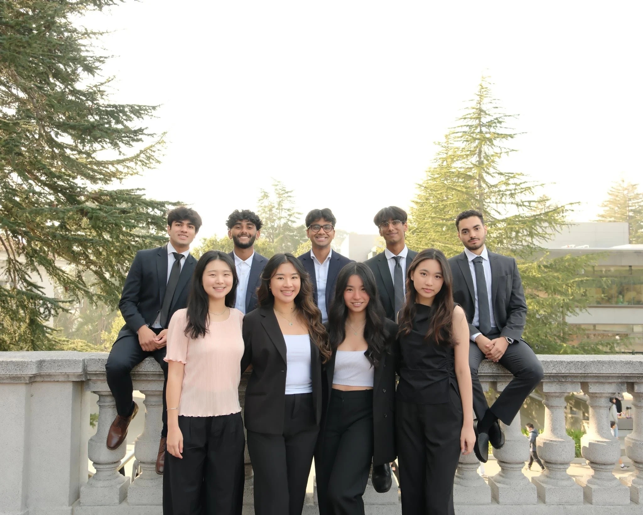 Nine members of the Health Engine team posing outdoors beside a stone balustrade