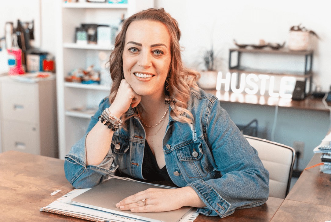Heather Holmes seated at a desk with a laptop in a bright workspace