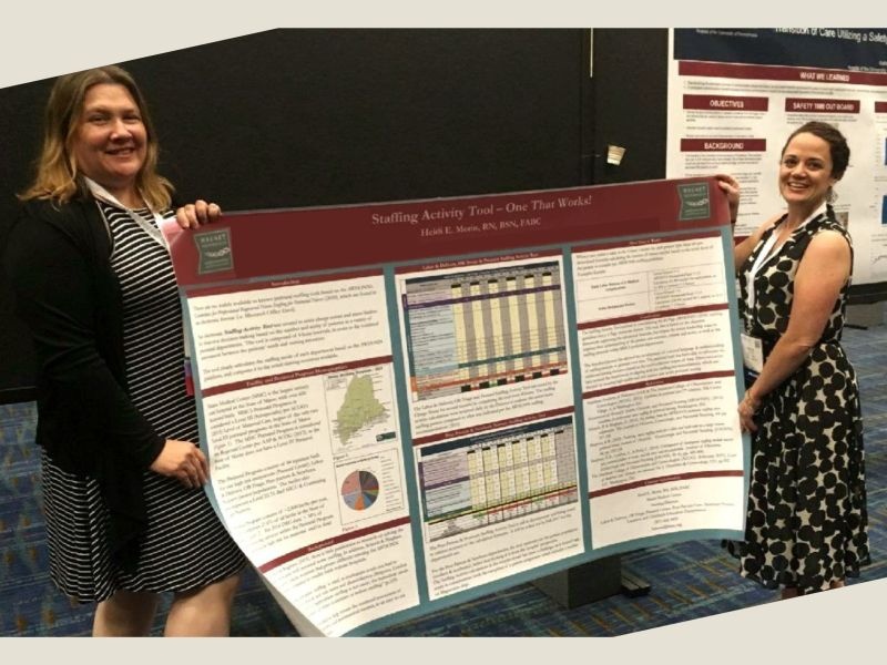 Heidi Morin and Sarah Austin holding the early staffing activity tool poster at a conference