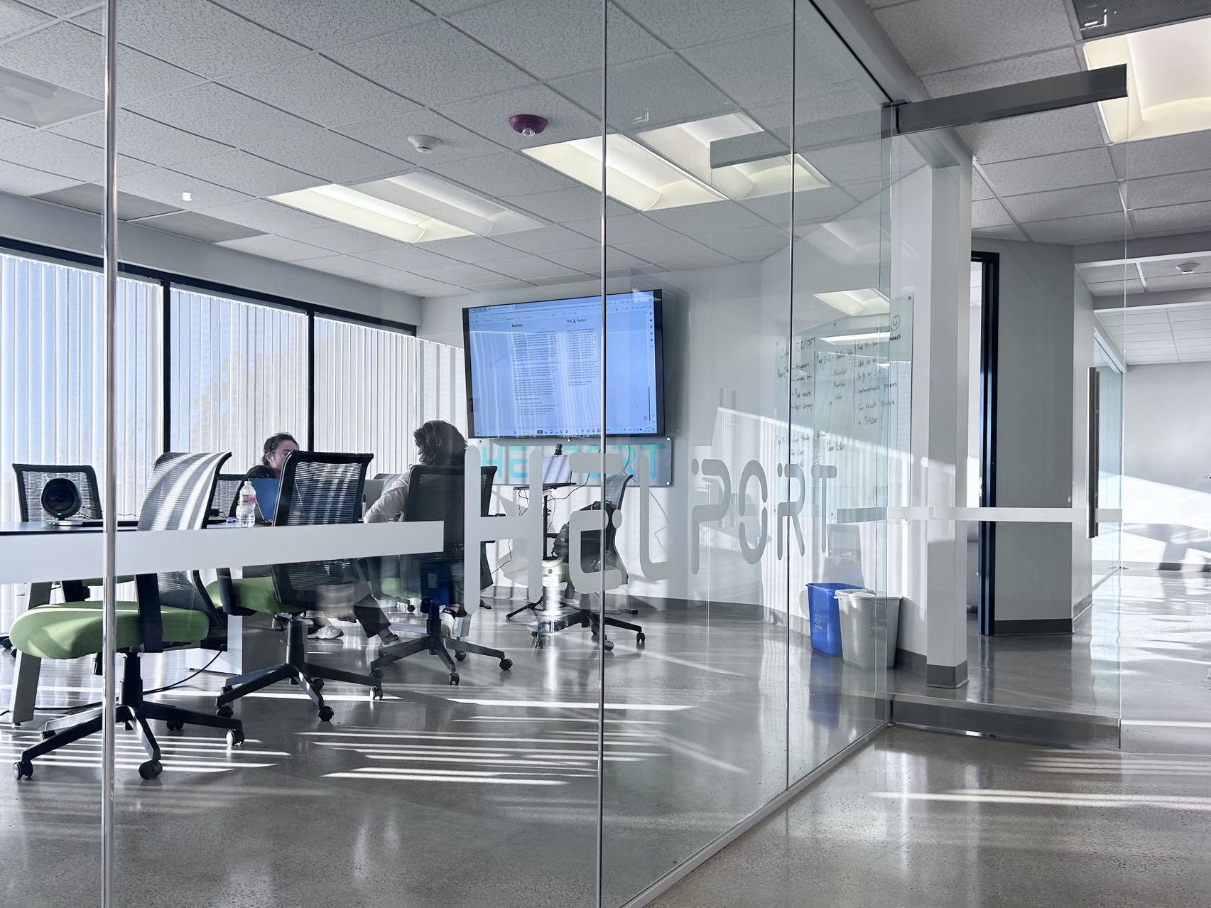A glass-walled Helport office meeting room with colleagues seated around a table