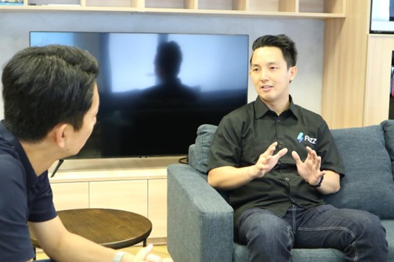 Hendra Kwik speaks with an interviewer while seated in an office