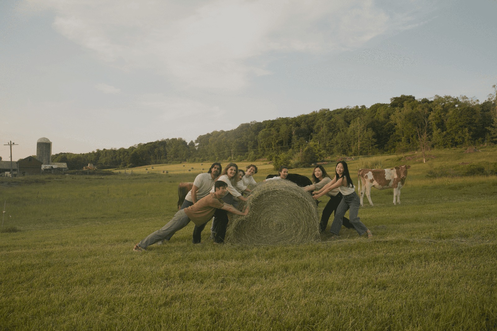 A group pictured on Hera’s company story page pushing a hay bale in a field