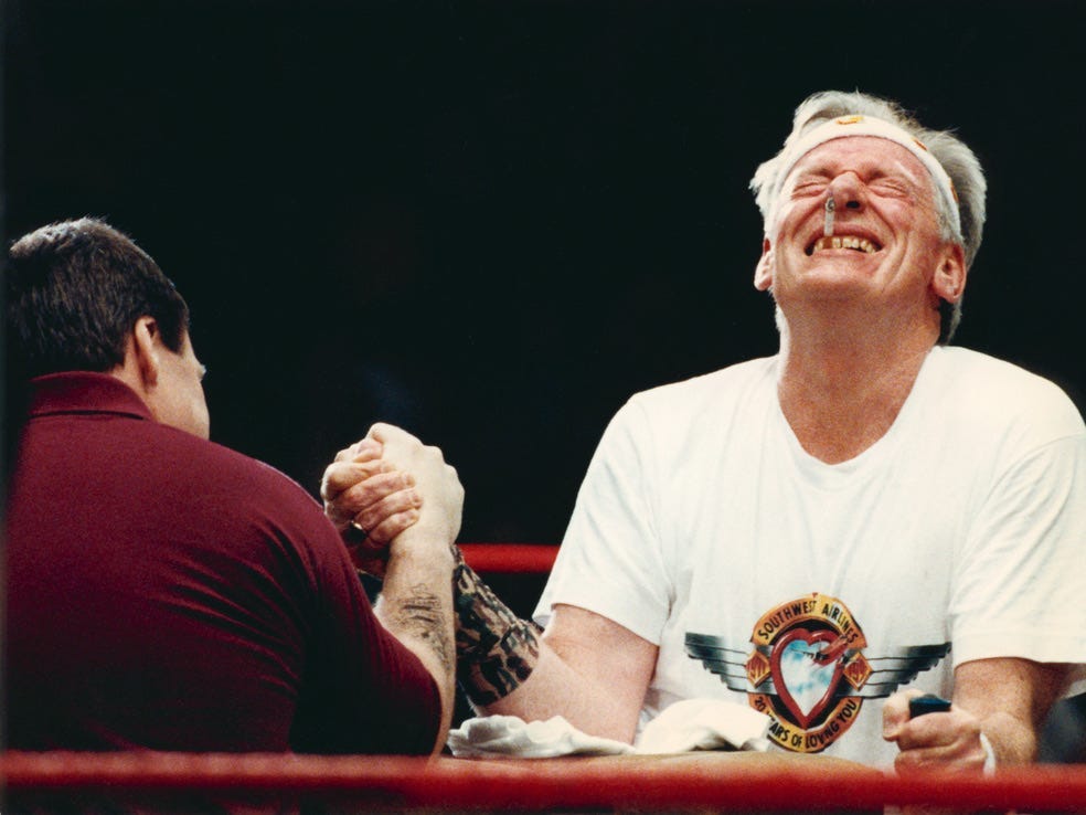 Herb Kelleher laughing as he arm-wrestles Kurt Herwald at the 1992 Malice in Dallas