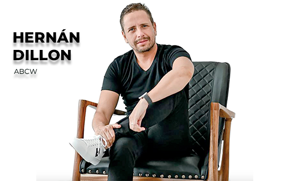 Hernán Dillon Noval seated in an armchair, wearing a black shirt and white sneakers