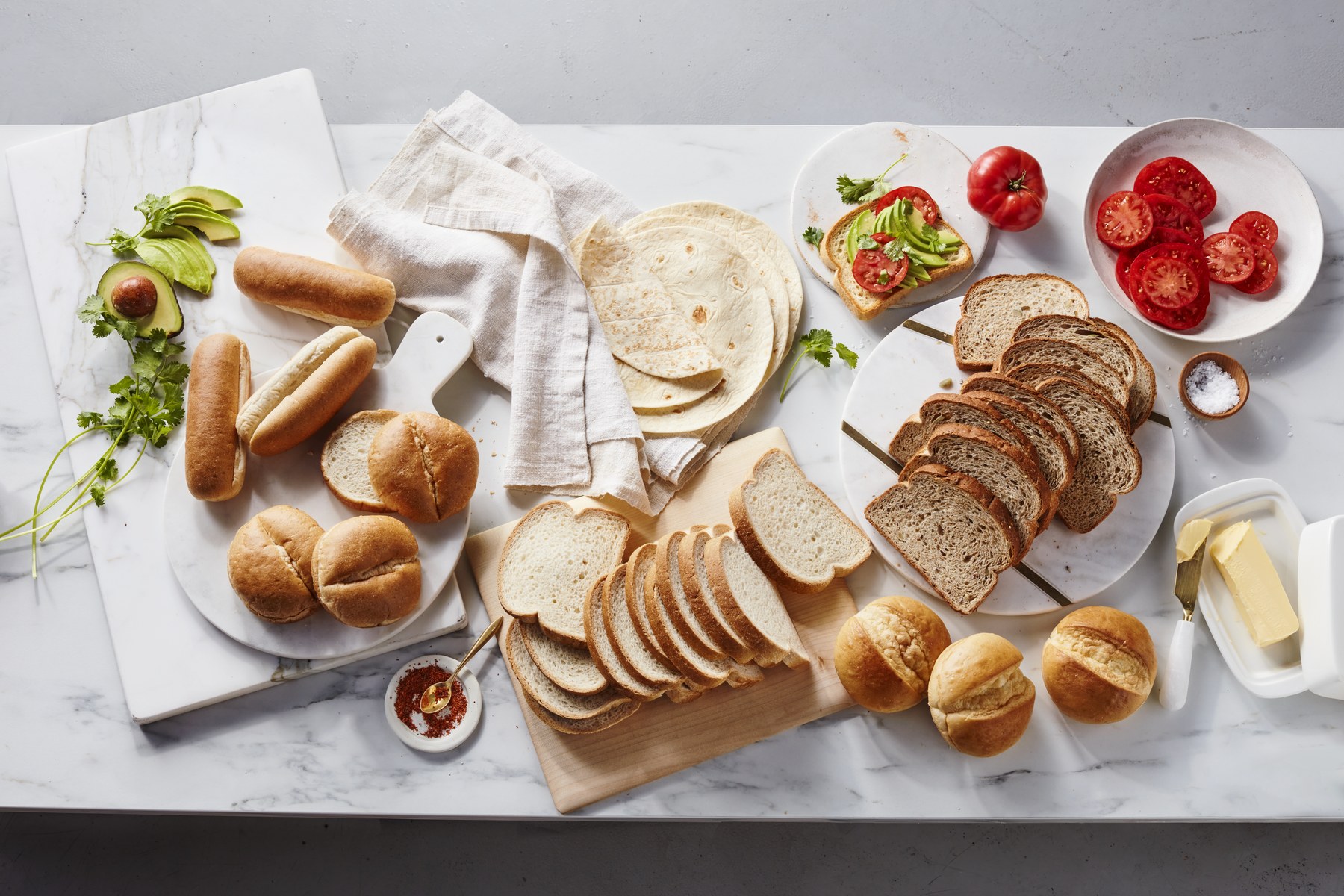 An overhead spread of Hero Bread loaves, buns, tortillas and rolls on a marble table