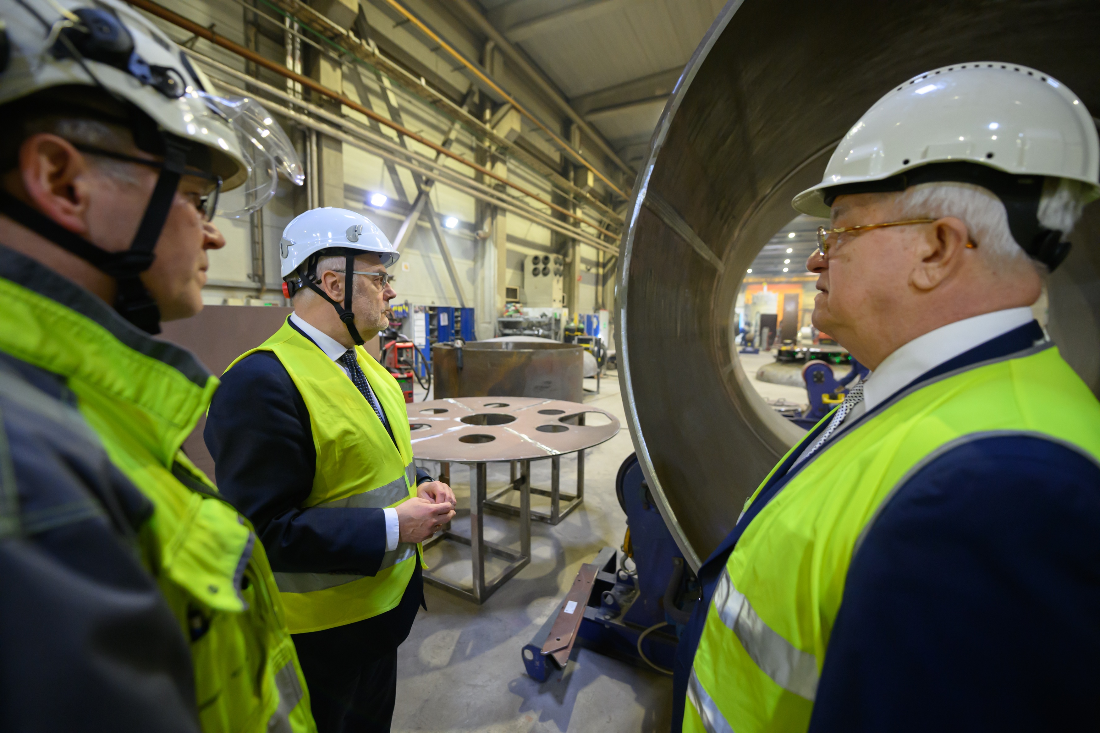 President Alar Karis and Estanc representatives wearing safety helmets and high-visibility vests on the production floor
