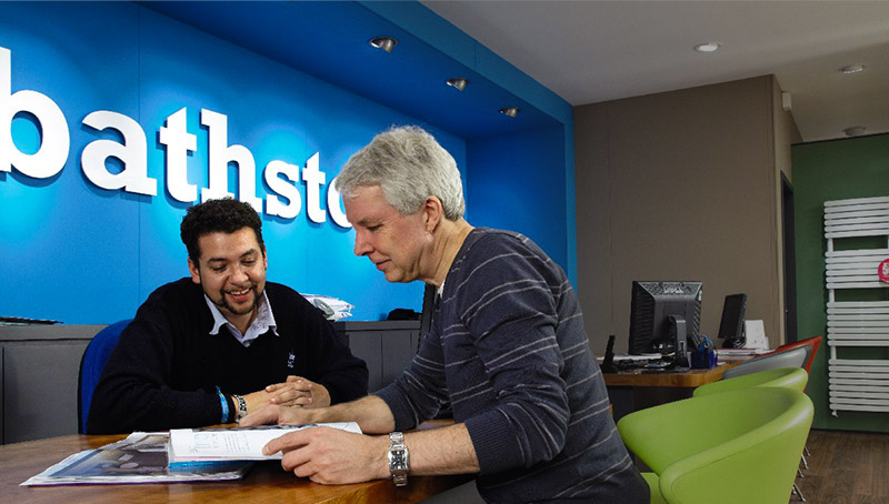 Two people reviewing plans at a bathstore showroom counter
