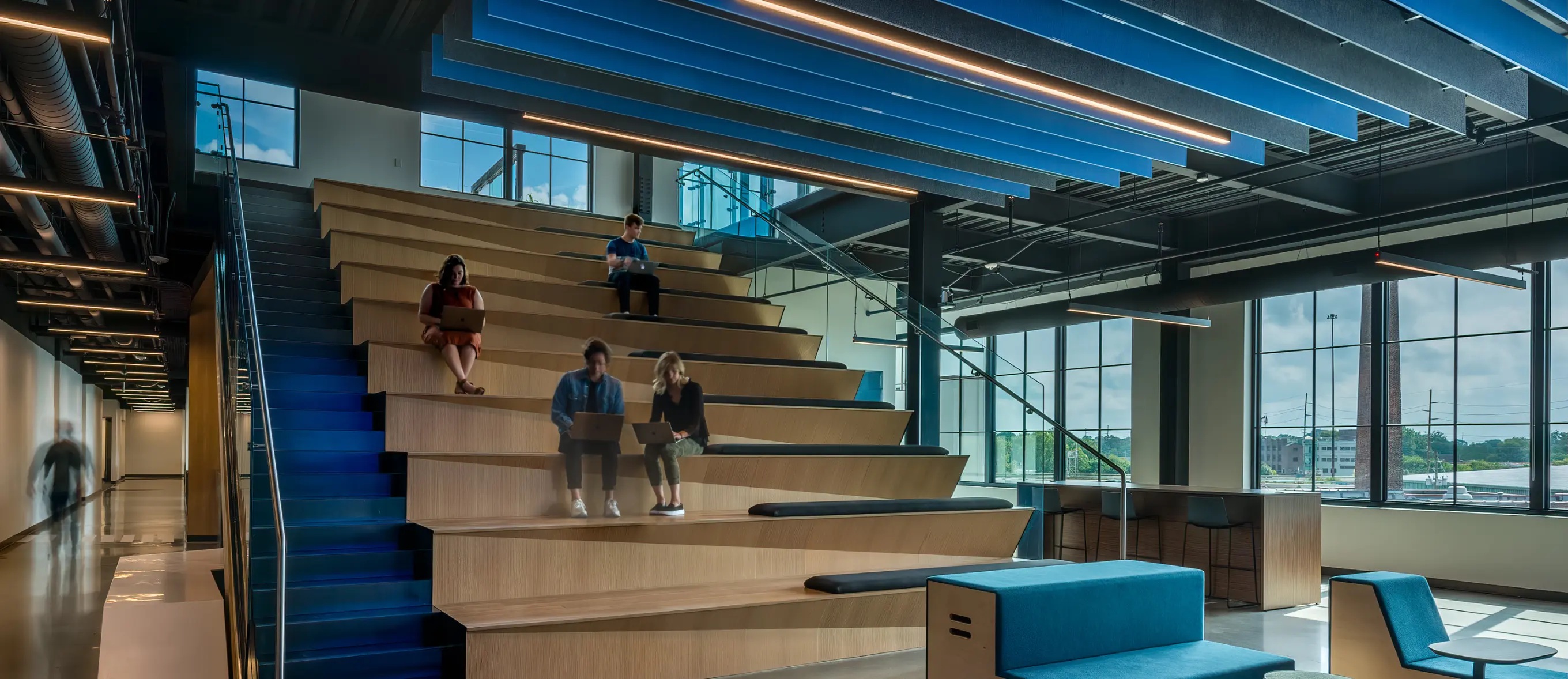 People working on laptops on the broad wooden staircase inside High Alpha’s office