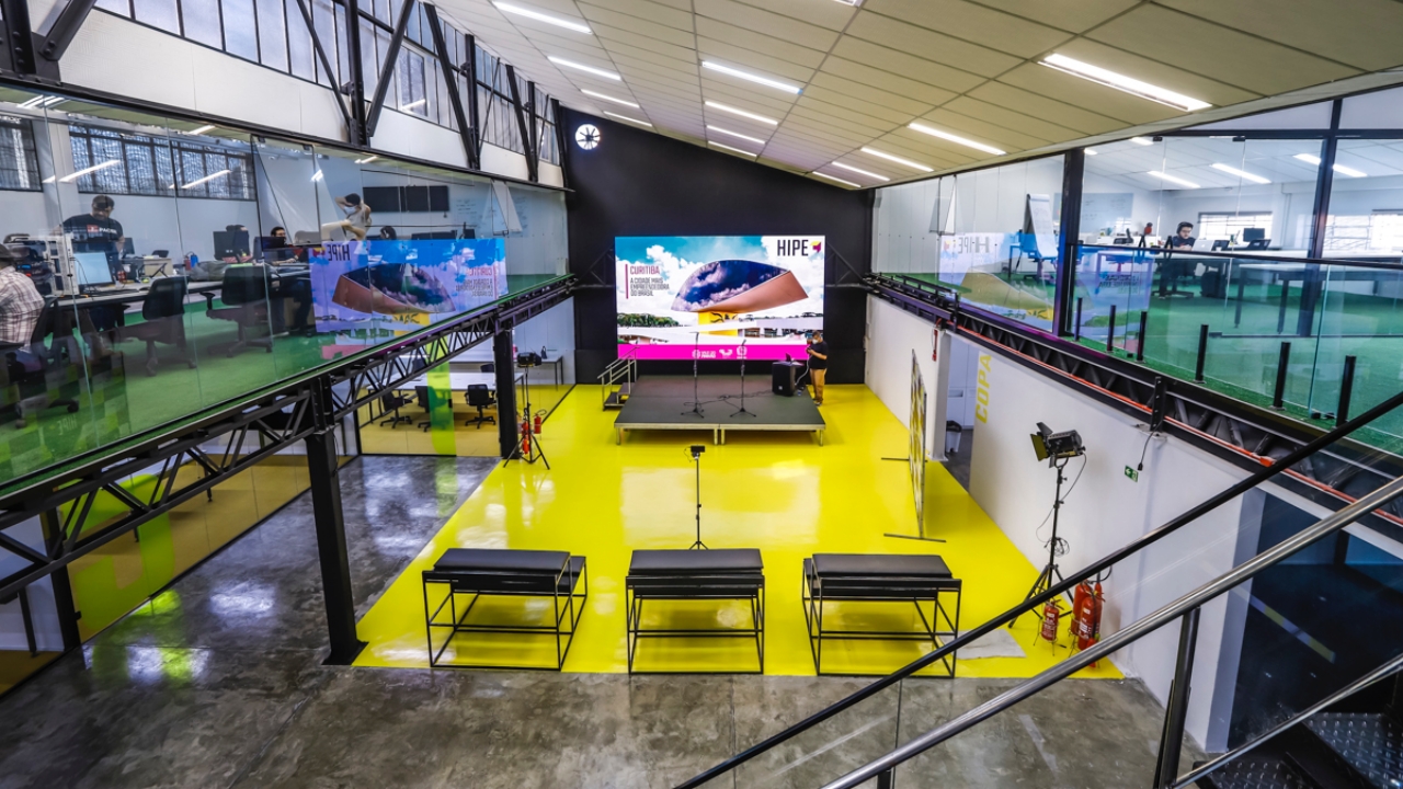 HIPE’s central yellow event floor and stage, flanked by glass-fronted workspaces