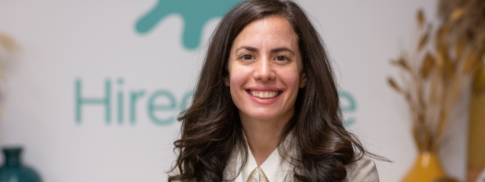 HiredScore founder Athena Karp smiling in front of the company's wordmark