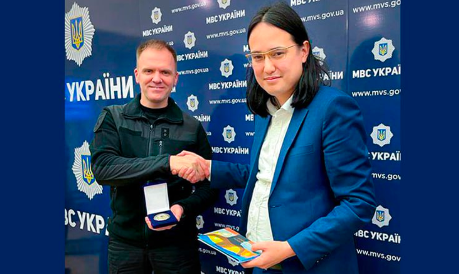 Deputy Minister Leonid Tymchenko shakes hands with Hoan Ton-That, who holds a presentation case and books.