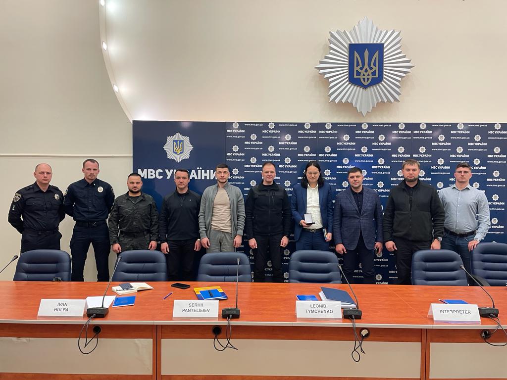 Hoan Ton-That, in a blue suit, stands with Ukrainian officials behind a conference table in April 2023.