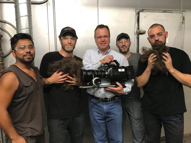Larry Hobbs holding a television camera with the How It’s Made crew at the factory