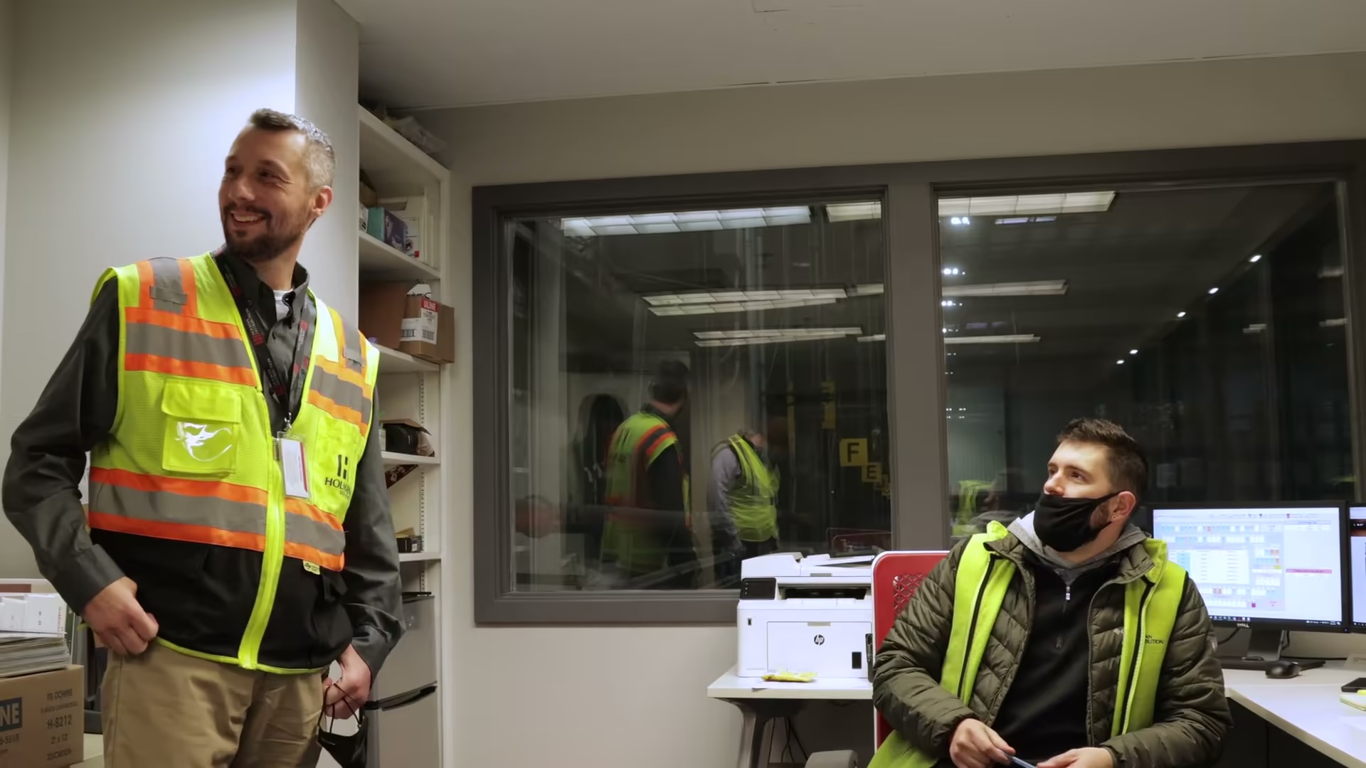 Holman team members wearing high visibility vests in a warehouse office