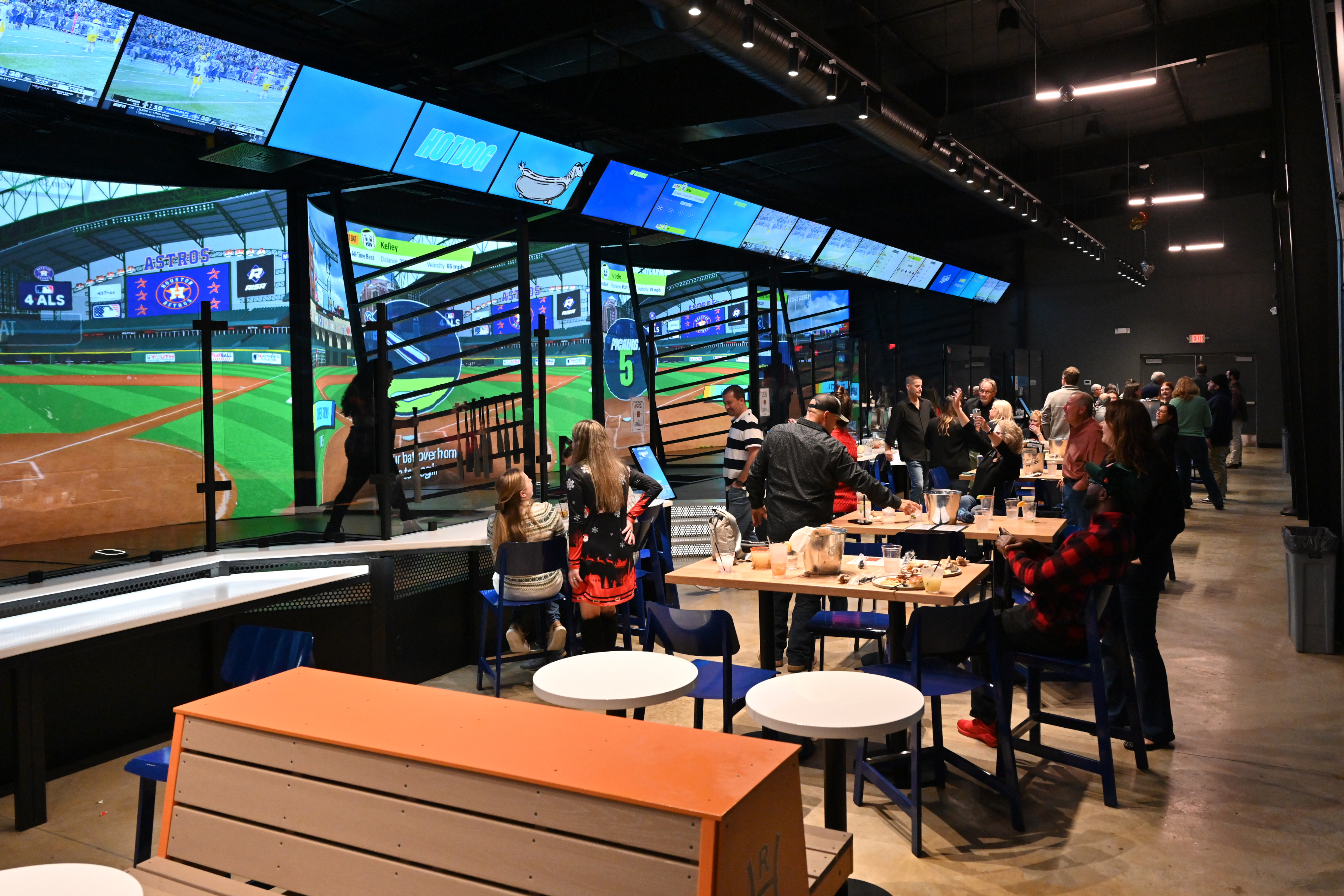 Guests dining beside Home Run Dugout’s illuminated simulated batting bays