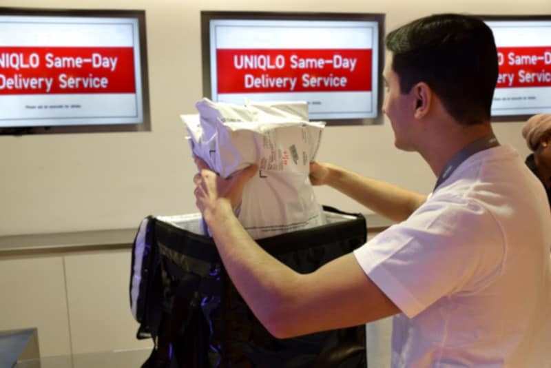 A courier prepares a retail package for same-day delivery at a Uniqlo service counter