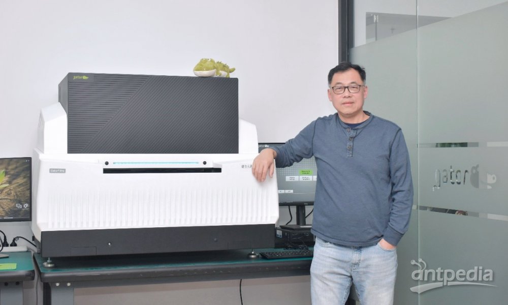 Hong Tan standing beside a Gator Bio instrument, with a small alligator toy on top