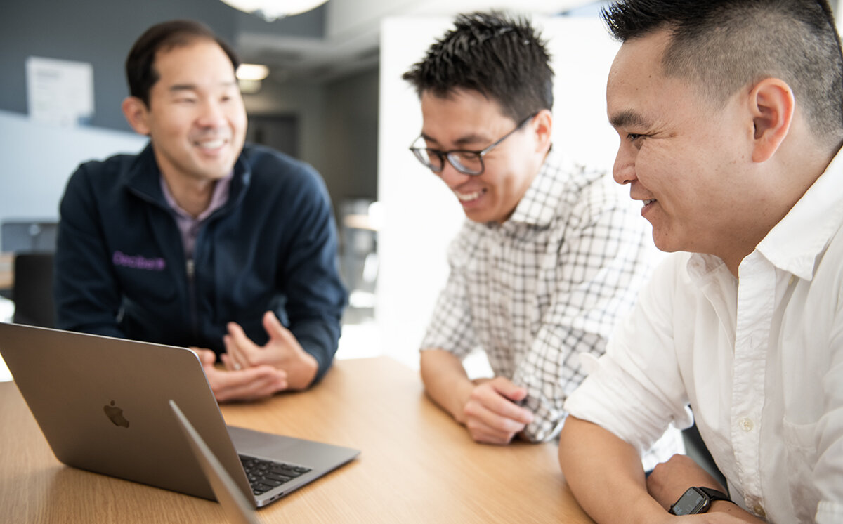 Hong Wang and the early Akuity team discussing work around a laptop