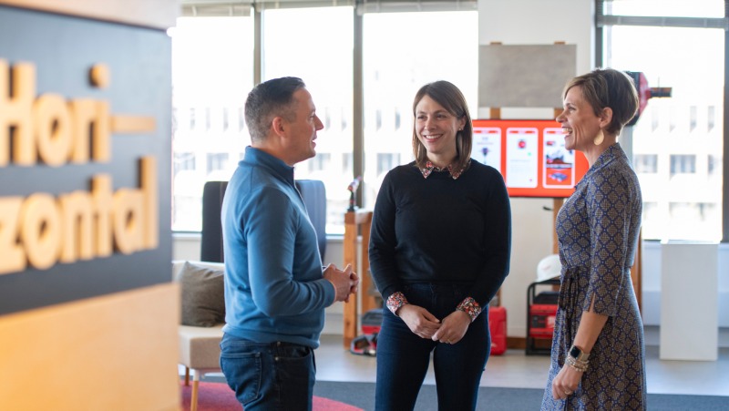 Three people talking in a bright Horizontal office