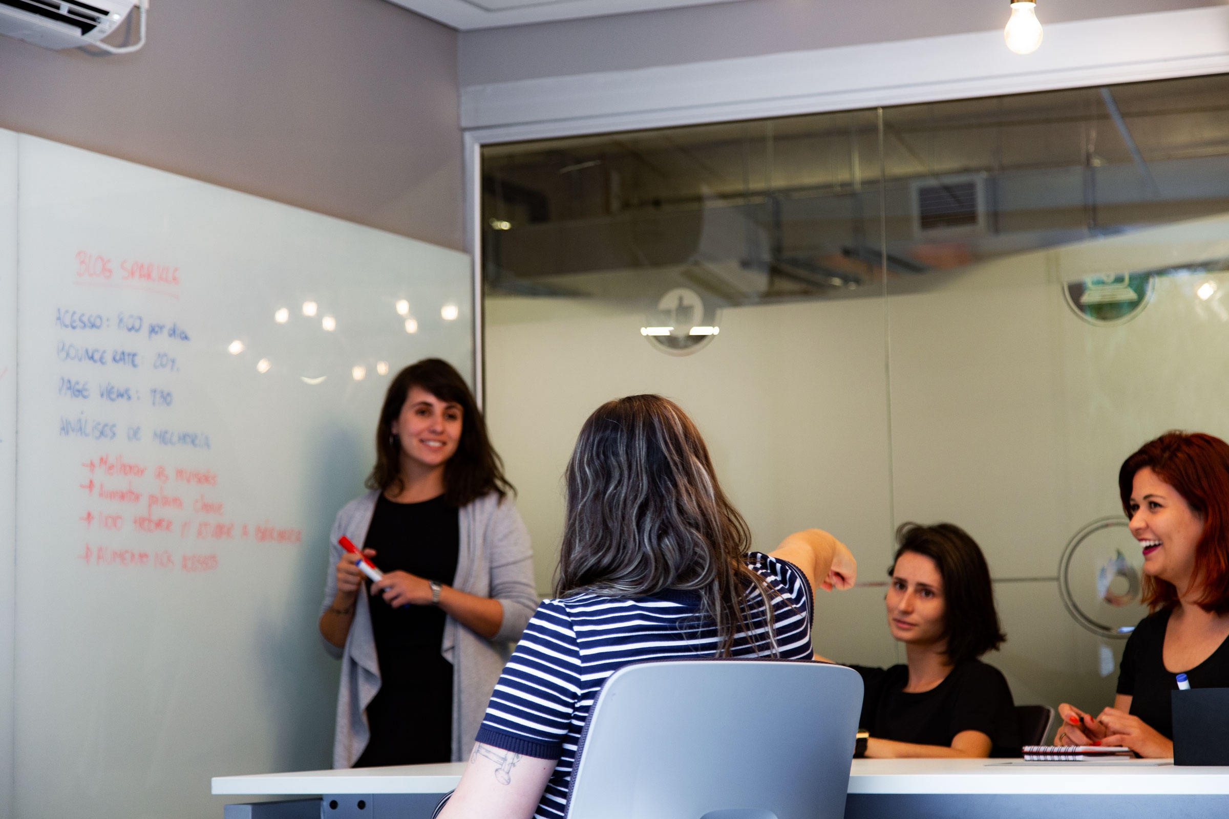 Hotmart employees exchanging ideas around a table in an office
