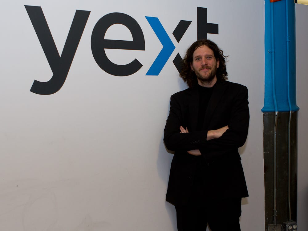 Howard Lerman standing beside a large Yext logo in the company's early office