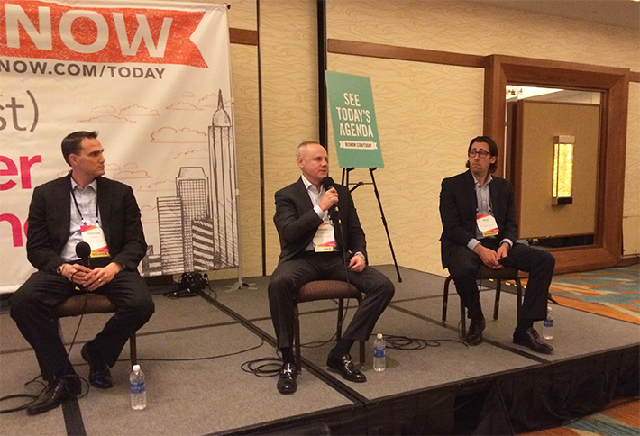 Howard Schwimmer, seated at center with a microphone, speaking on an industrial real estate panel alongside Jonathan Pharris and Brian Gagne.