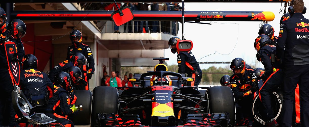 Red Bull Racing mechanics working around a car in the pit lane